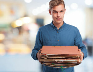 Manager fatigué portant une pil de dossier, illustrant la surcharge de travail due à une mauvaise délégation