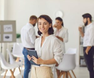 une femme avec un cahier dans les mains s'affirme devant groupe de personnes qui discutent